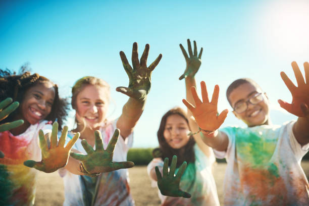 Picture of multicultural group of kids smiling and high fiving with paint on their hands
